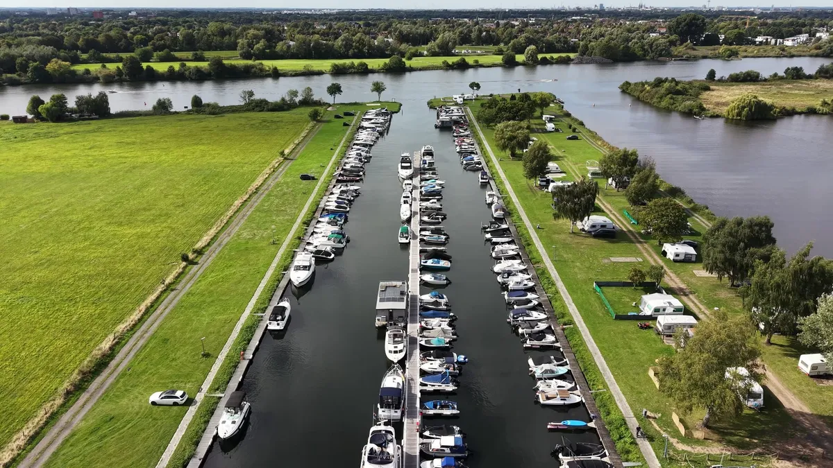 Luftaufnahme über dem Hafenbecken: Motorboote liegen an drei Stegreihen, rechts die Weser, im Hintergrund Bremen