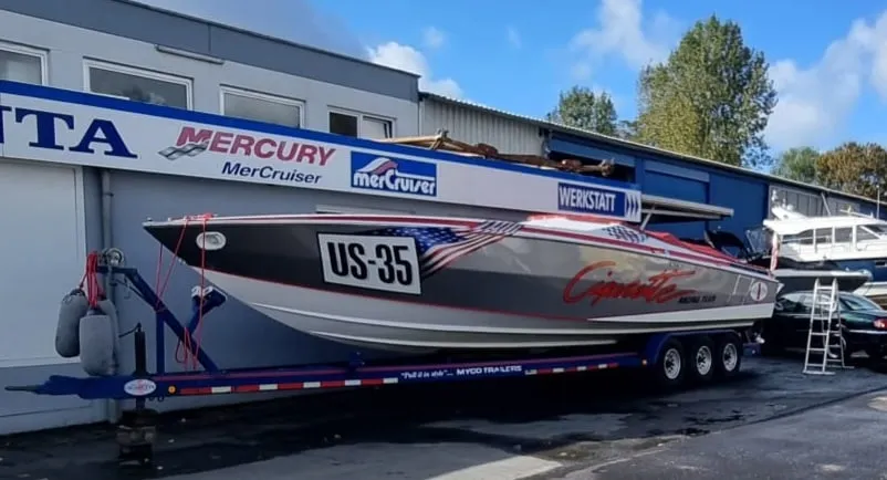 Ein Offshore-Rennboot auf einem Dreiachs-Trailer vor einer Werkstatt mit Mercury- und MerCruiser-Schriftzug